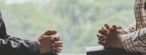 Two Man Sit On Wooden Chair While Praying To God Together In Hom